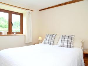 a bedroom with a white bed and a window at The Dairy At Copper Beeches in Petersfield +6 photos