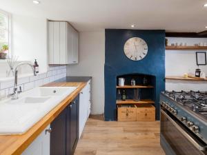 a kitchen with a sink and a clock on the wall at Hurst Cottage in Sturminster Newton +9 photos