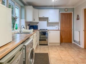 a kitchen with white cabinets and a washer at Heron's Lodge in Llanarthney