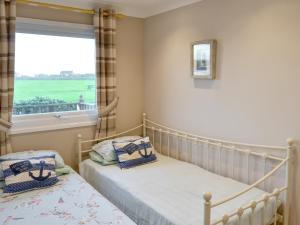 two twin beds in a bedroom with a window at On The Beach in Bacton +10 photos