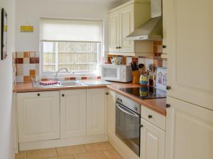 a kitchen with white cabinets and a sink and a microwave at On The Beach in Bacton