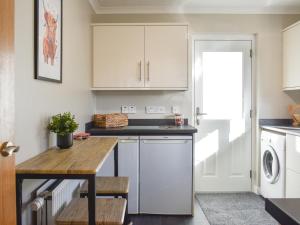a kitchen with white cabinets and a wooden table at Cathwill in Newtonmore