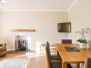 a dining room with a table and a fireplace at Cathwill in Newtonmore