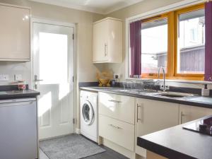 a kitchen with white cabinets and a washer and dryer at Cathwill in Newtonmore