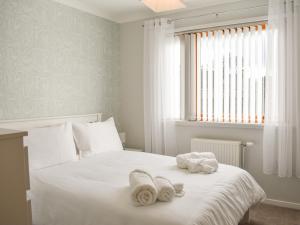 a bedroom with a white bed with towels on it at Cathwill in Newtonmore +6 photos