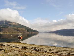 a boat is sitting on the shore of a lake at Sanna in Ardentinny