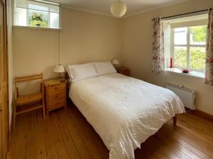 a bedroom with a white bed and two windows at Sanna in Ardentinny