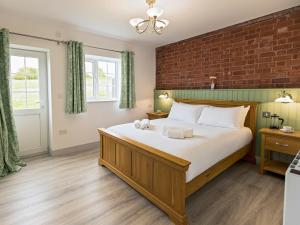 a bedroom with a large bed with a brick wall at Foxwhelp in Ledbury