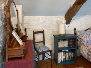 a bedroom with a chair a mirror and a book shelf at Y Smithy - Uk49022 in Llanybyther +2 photos