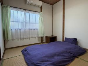 a bedroom with a large purple bed and a window at Omuta Cozy Stay in Ōmuta