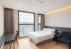 a bedroom with a bed and a desk and a large window at Celib Yeoui in Seoul