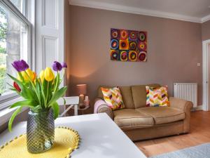 a living room with a couch and a table with flowers at The Leveret in Aberlady