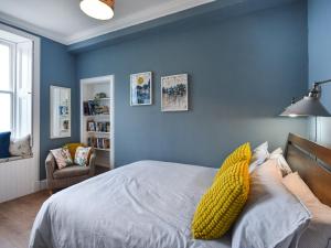 a bedroom with blue walls and a bed with yellow pillows at The Leveret in Aberlady