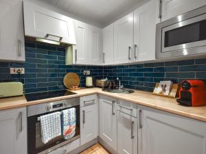 a kitchen with white cabinets and blue tiles at The Leveret in Aberlady