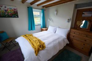 a bedroom with a white bed with a yellow blanket on it at Golan - Ukc4677 in Clynnog-fawr