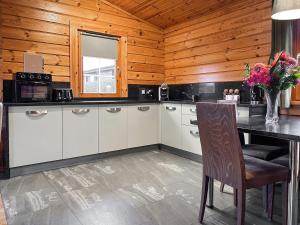 a kitchen with white cabinets and a table and a window at Lodge 4 - Uk51264 in Glasgow