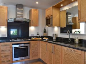 a kitchen with wooden cabinets and black counter tops at Y Bwthyn At Tyddyn Obry in Llanfaelog