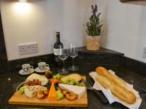 a table with a cutting board with food and wine glasses at Y Bwthyn At Tyddyn Obry in Llanfaelog
