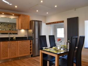 a kitchen with a table and a stainless steel refrigerator at Y Bwthyn At Tyddyn Obry in Llanfaelog +9 photos