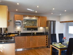 a kitchen with wooden cabinets and a stainless steel refrigerator at Y Bwthyn At Tyddyn Obry in Llanfaelog