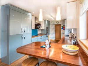 a kitchen with a wooden table and blue cabinets at Beinn View House in Cononbridge
