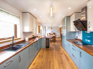 a kitchen with blue and white cabinets and wooden floors at Beinn View House in Cononbridge