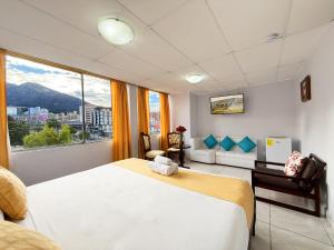 a bedroom with a large bed and a large window at Hotel Santamaria en quito in Quito