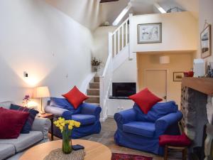 a living room with blue couches and red pillows at Gushat Cottage in Strathtay