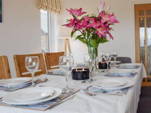a table with plates and glasses and a vase of flowers at Bernicia House in Seahouses