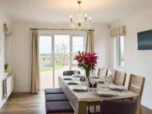 a dining room with a table with a vase of flowers at Bernicia House in Seahouses