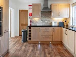 a kitchen with wooden cabinets and black counter tops at Bernicia House in Seahouses +22 photos