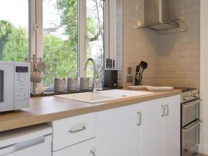 a kitchen with white cabinets and a sink and a window at The Snug in Bowness-on-Windermere