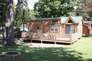 Cabaña de madera con porche y árbol en Lakeland RV Campground Deluxe Loft Cabin 11, en Edgerton