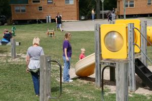 two women and a child playing in a playground at Lakeland RV Campground Deluxe Loft Cabin 11 in Edgerton
