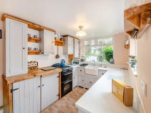 a kitchen with white cabinets and a stove top oven at Lillie's Cottage in Sewerby