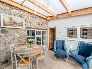 a dining room with a table and chairs and a stone wall at Lillie's Cottage in Sewerby