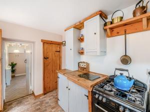 a kitchen with a stove top oven next to a hallway at Lillie's Cottage in Sewerby +9 photos