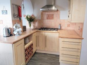 a kitchen with wooden cabinets and a stove top oven at Croeso in Conwy