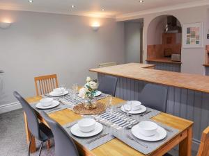 a dining room with a table with chairs and a kitchen at Croeso in Conwy
