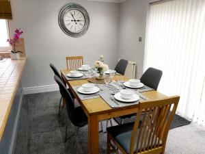 a dining room table with chairs and a clock on the wall at Croeso in Conwy +14 photos