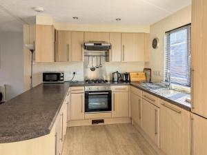 a kitchen with wooden cabinets and a stove top oven at Bowness Lodge 12 Fellside in Windermere