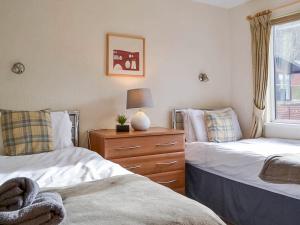 a bedroom with two beds and a dresser and a window at Bowness Lodge 12 Fellside in Windermere +6 photos