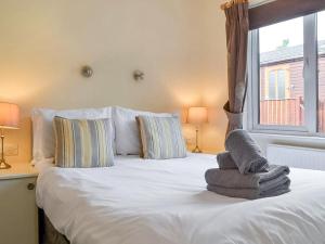 a bedroom with a white bed with pillows and a window at Bowness Lodge 12 Fellside in Windermere