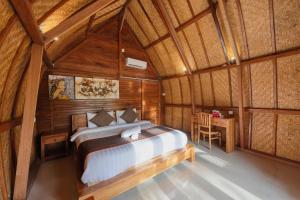 a bedroom with a bed in a wooden room at The Tandjung Cottage in Nusa Penida
