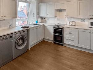 a kitchen with white cabinets and a washer and dryer at India Lane Cottage in Montrose