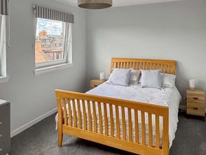 a bedroom with a wooden bed and a window at India Lane Cottage in Montrose