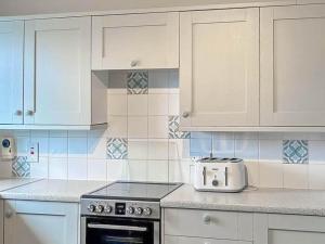 a kitchen with white cabinets and a stove top oven at India Lane Cottage in Montrose
