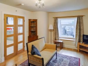 ein Wohnzimmer mit einem Sessel und einem Fernseher in der Unterkunft Old Steading in Brodick
