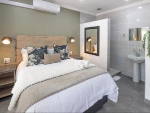 a bedroom with a large bed and a sink at Sage Haven Guesthouse in Modimolle
