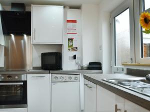a kitchen with white cabinets and a microwave at Lle Clyd in Harlech
